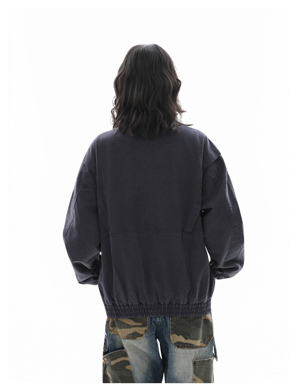 Back view of a model wearing a charcoal oversized jacket with an elastic hem and camouflage trousers.