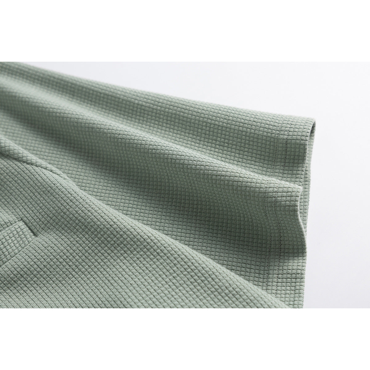 Close-up of a sage-green textured short sleeve and its finished cuff.
