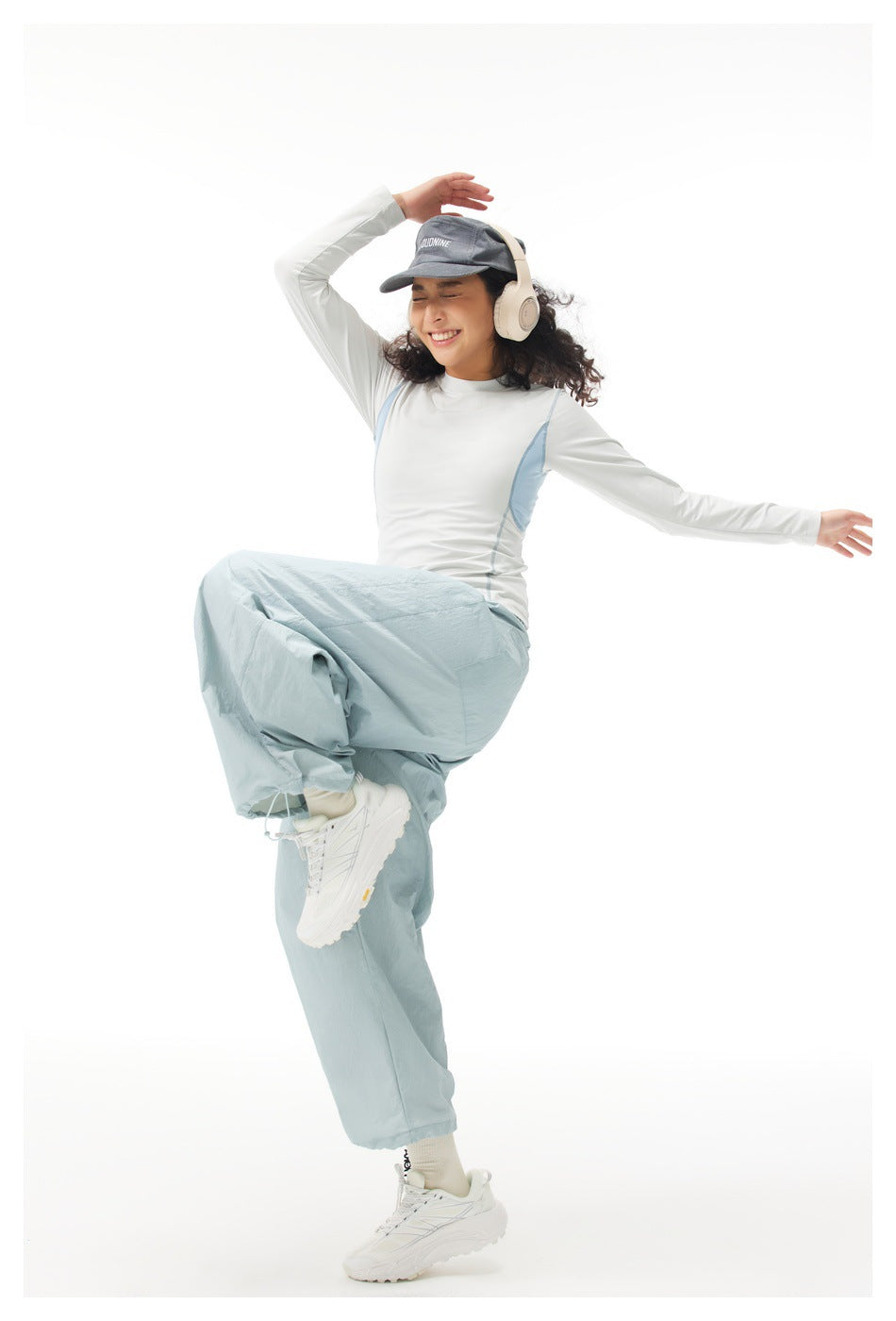 Full-length model wearing a white long-sleeve top with pale blue side panels and loose light blue pants.