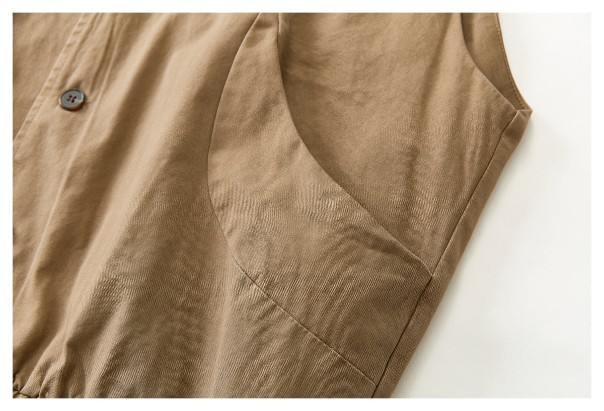 Close-up of a tan vest's side panel, curved armhole seam, and dark button.