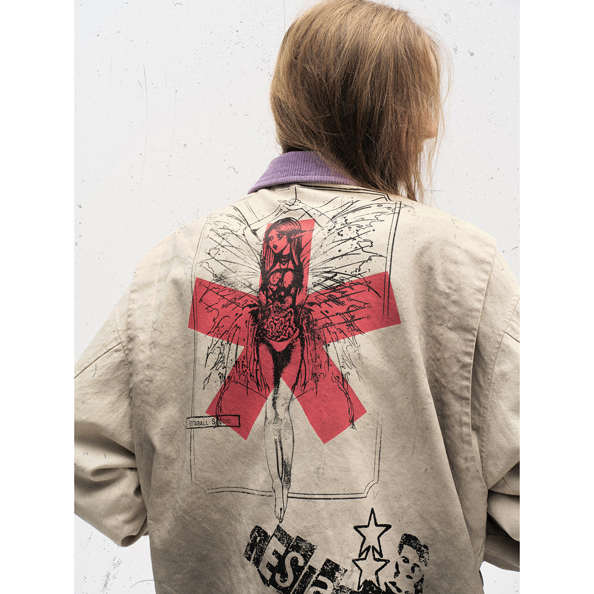 Back view of a model wearing a distressed beige jacket with a large red-and-black illustrated graphic.