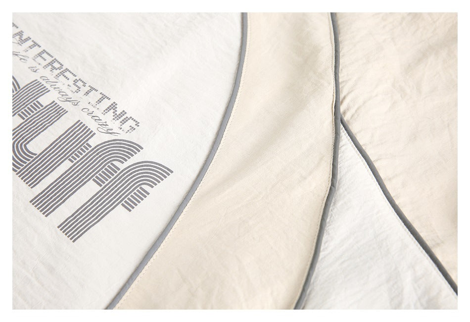 Close-up of cream and white fabric panels edged with gray piping.