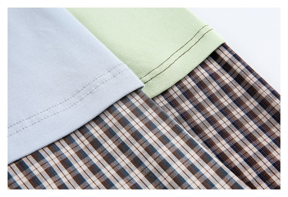 Close-up of pale blue and pale green garment hems over brown, blue, and cream plaid fabric.