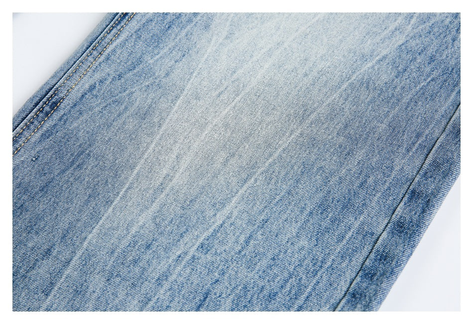 Close-up of a light blue washed denim leg with faded texture and a stitched seam.