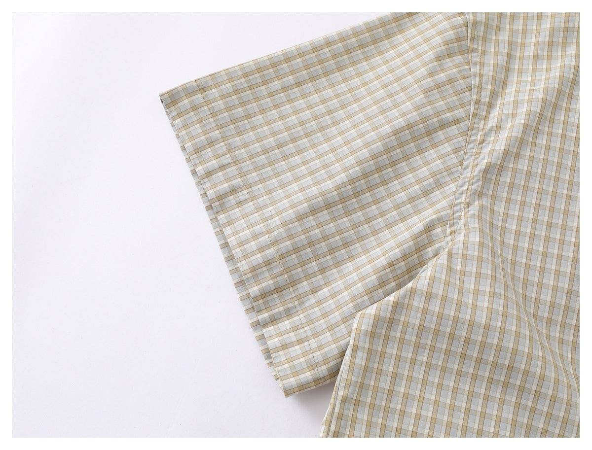 Close-up of a beige, white, and muted brown plaid shirt with a folded sleeve edge.