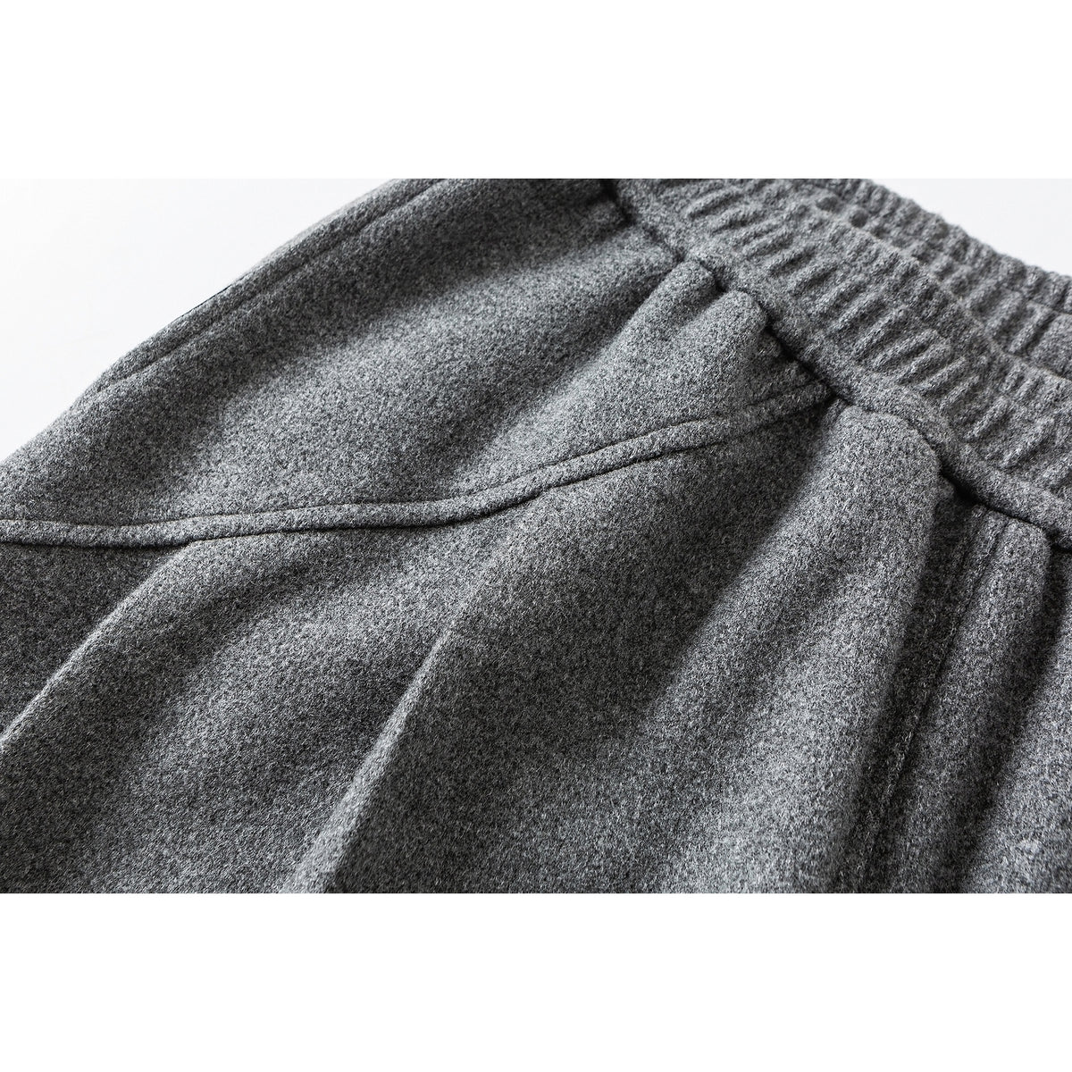 Close-up of gray pants showing the textured fabric, gathered waistband, and seam details.
