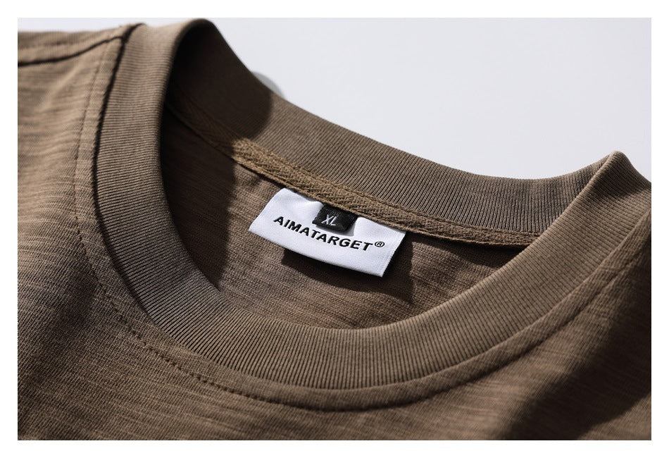 Close-up of the brown T-shirt's ribbed crew neck and sewn brand and size labels.