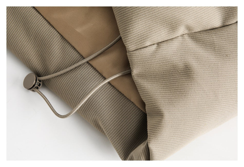 Close-up of a taupe ribbed garment with an adjustable cord and round toggle.