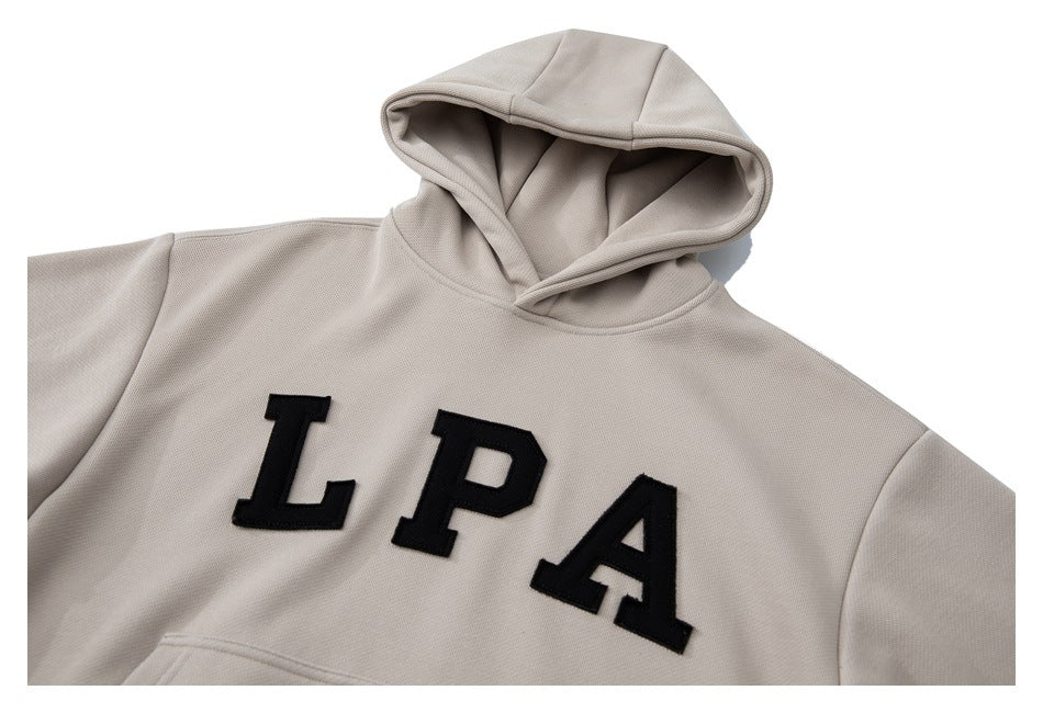 Front view of a light taupe hooded sweatshirt with bold black LPA lettering and a kangaroo pocket.