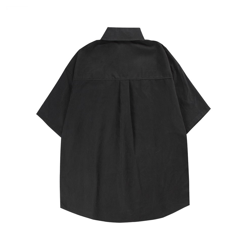 Back view of a black oversized short-sleeve collared shirt with a center pleat.