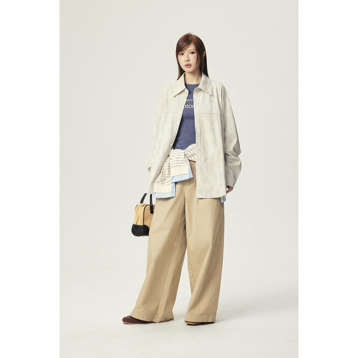 Model wearing an oversized cream button-front jacket with patch pockets and wide beige trousers.