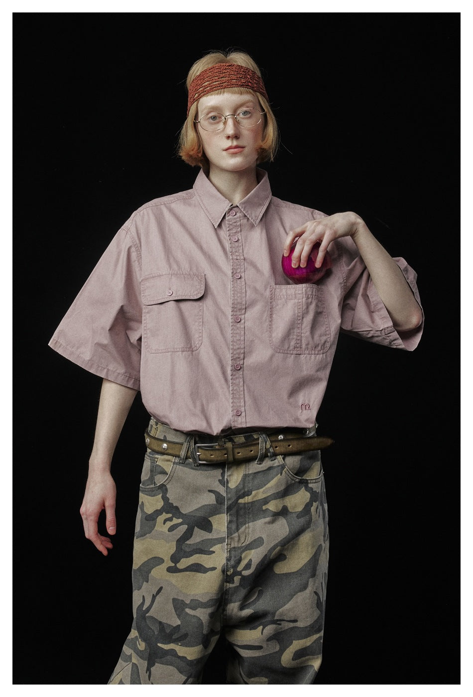 Model wearing a dusty pink button-up shirt with two chest pockets and camouflage pants.