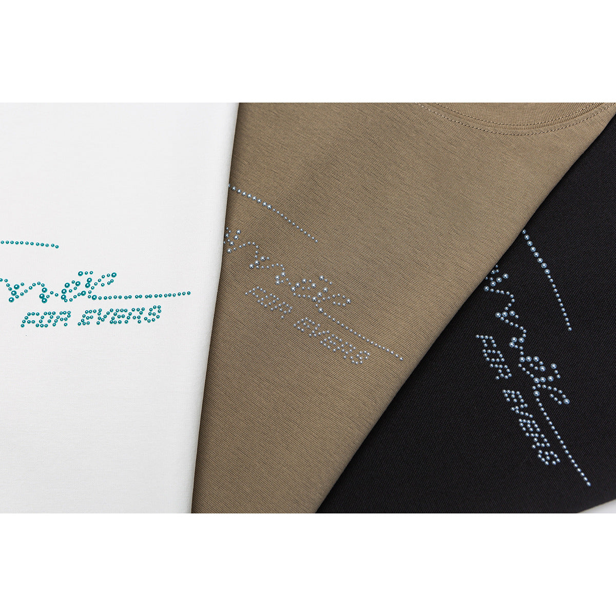 Close-up of rhinestone-style chest designs on white, brown, and black T-shirts.