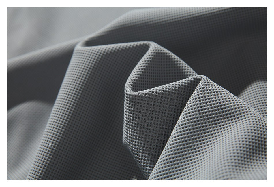 Gray grid-textured fabric gathered into folds, showing its surface and drape.