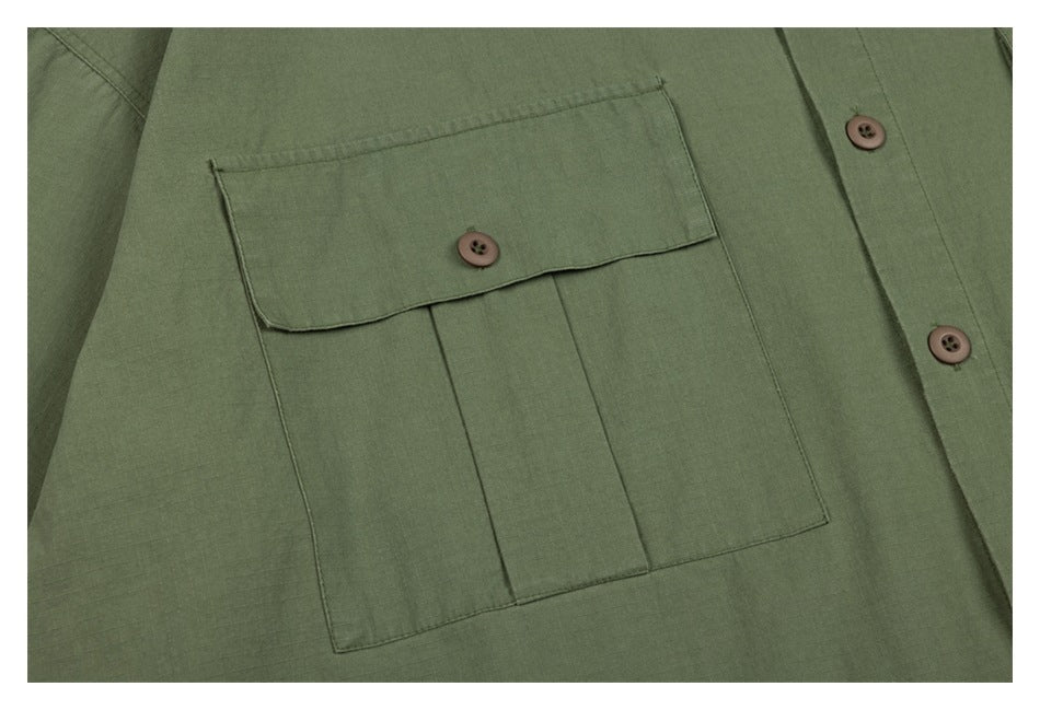 Close-up of the olive-green jacket's large pleated chest pocket with a buttoned flap.