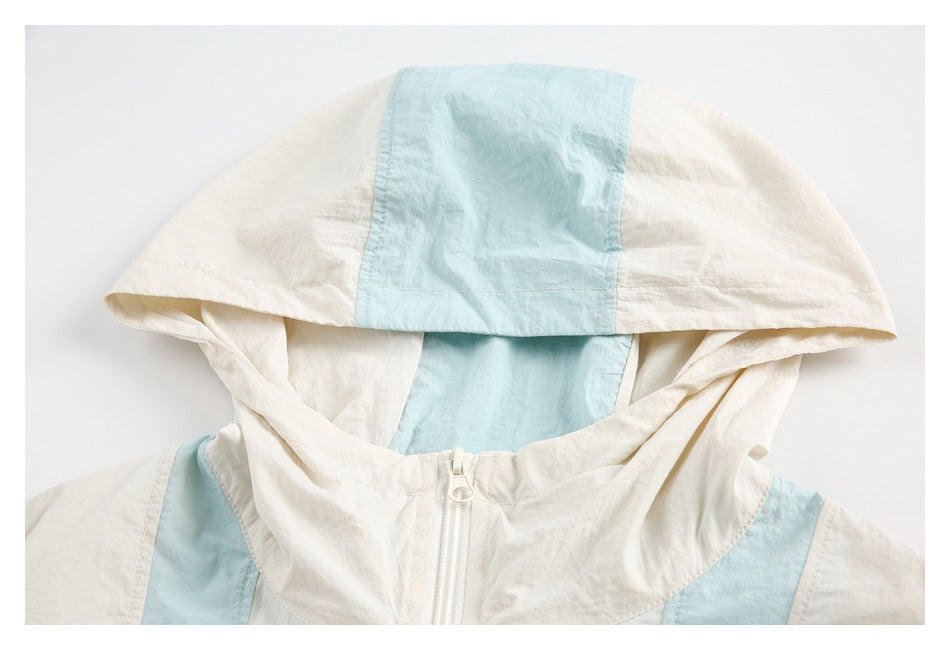 Close-up of a cream jacket hood with a pale blue center panel and the top of its front zipper.