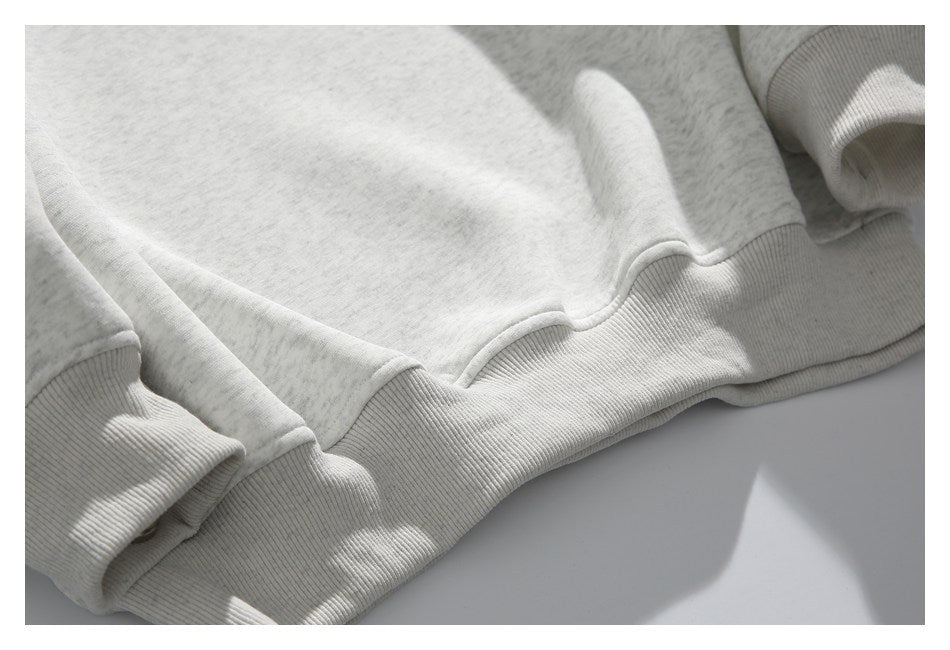 Close-up of the ribbed hem and cuff on a light gray heather sweatshirt.