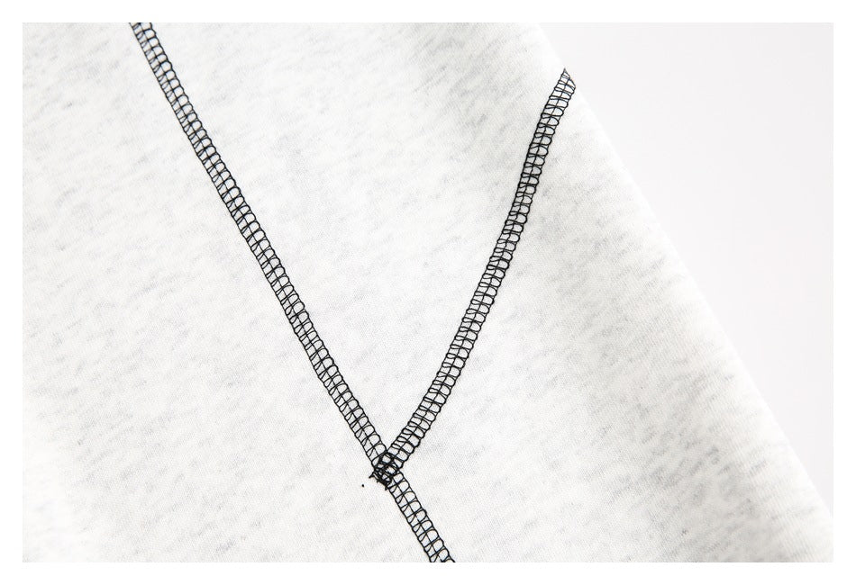 Close-up of intersecting black overlock seams on light gray garment fabric.