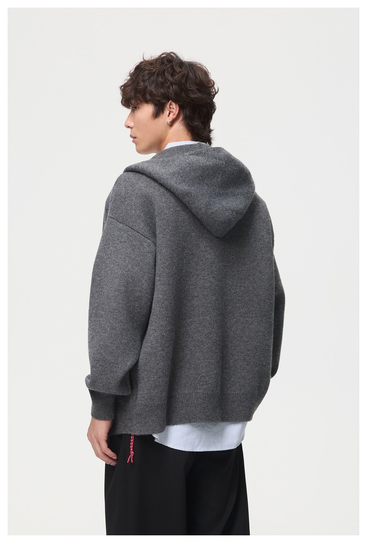 Close rear view of a model wearing a charcoal-gray hooded cardigan, showing its hood and relaxed fit.