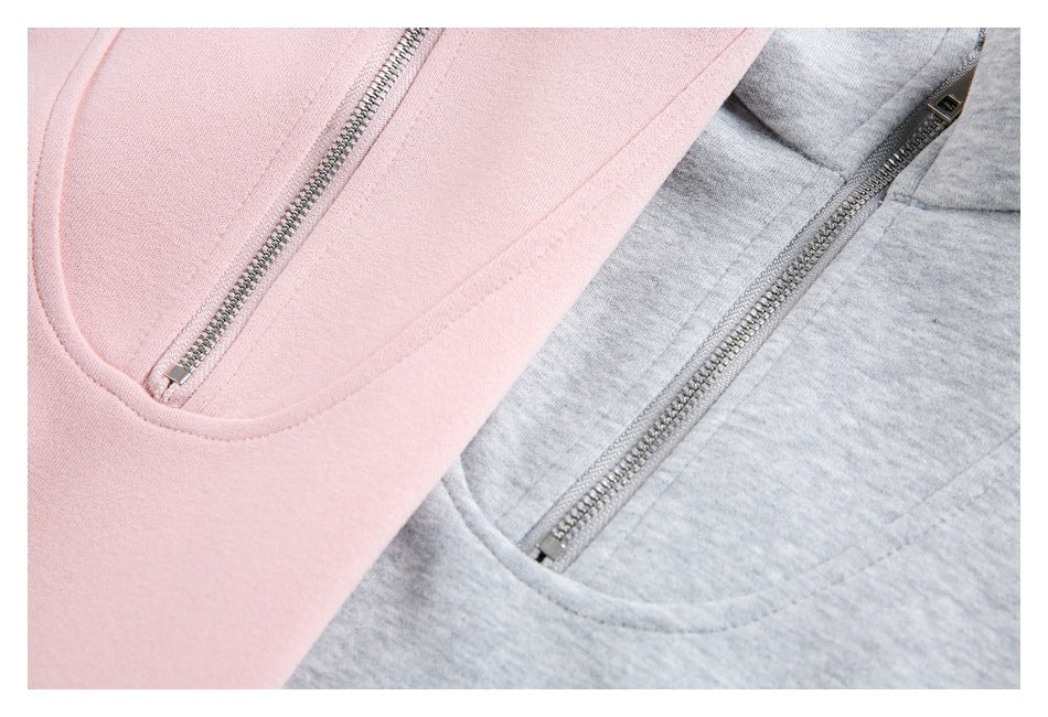 Close-up of pink and gray pullover fronts, highlighting the short metal zippers and curved seam detailing.