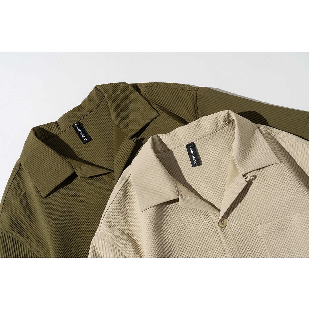 Close-up of beige and olive ribbed short-sleeve shirts showing their collars, buttons, and chest pockets.