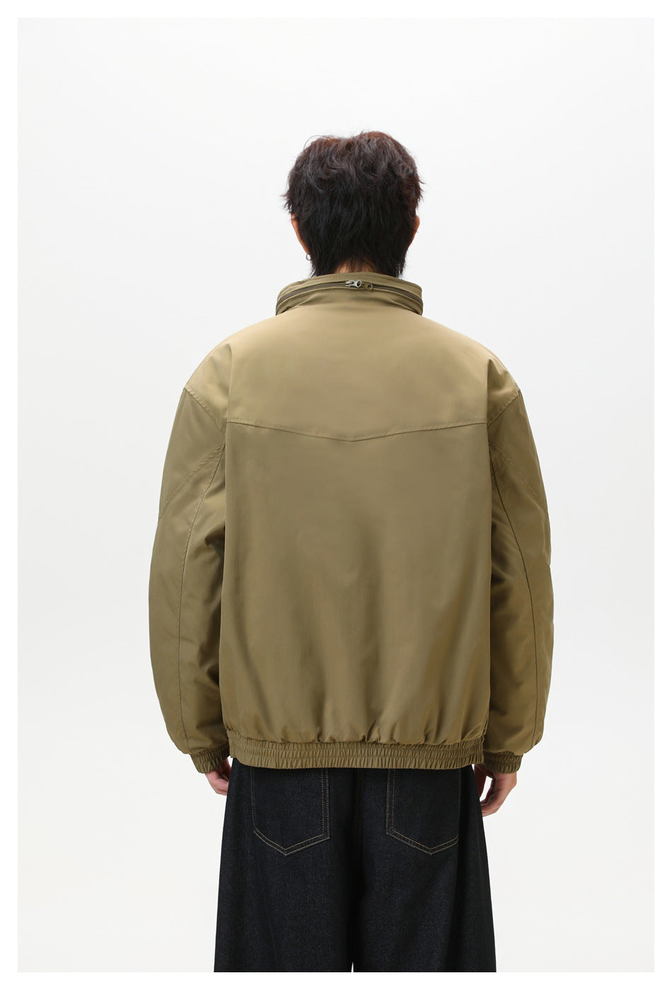 Rear view of a model wearing an olive-brown jacket with a yoke seam and elasticated hem and cuffs.
