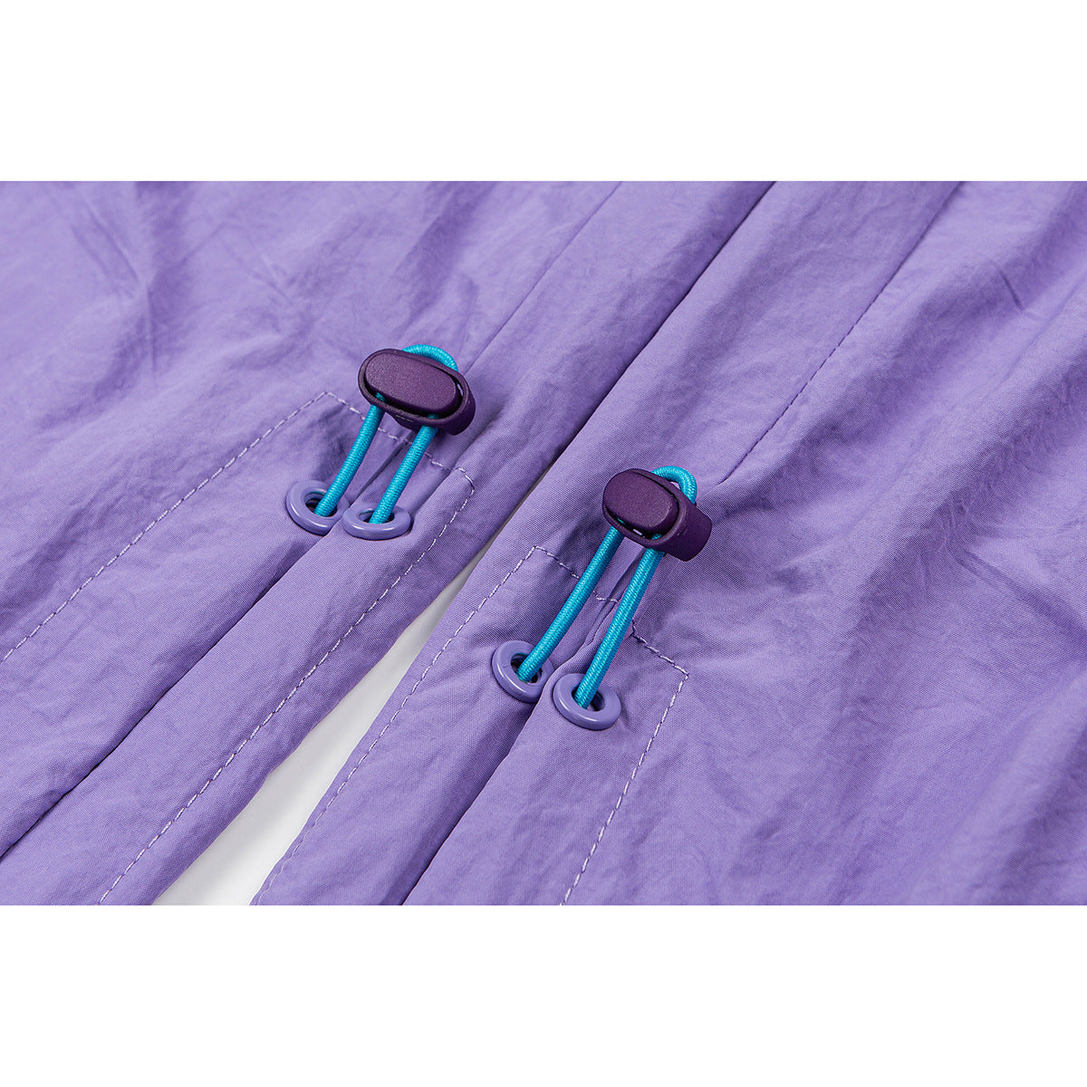 Close-up of turquoise drawcords and purple toggles on lavender pants.