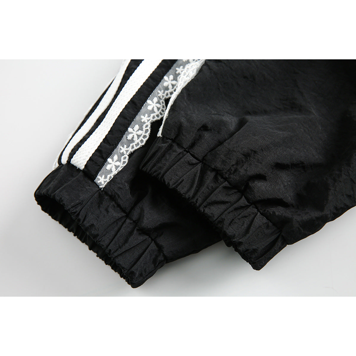 Close-up of the black jacket's gathered elastic cuffs and white sleeve stripes with floral lace trim.