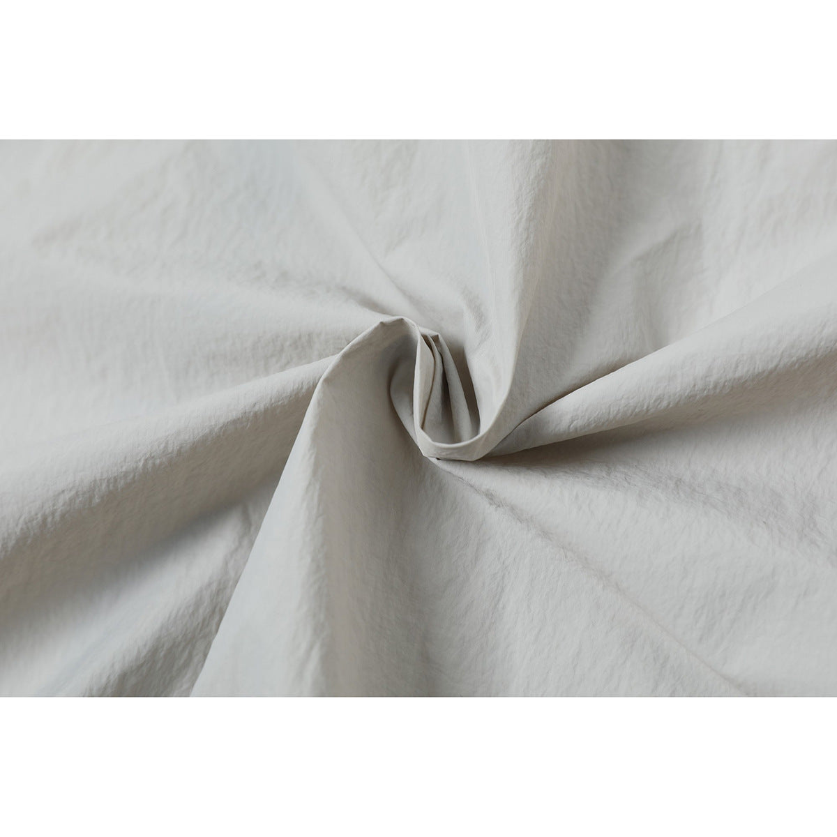 Close-up of light gray fabric gathered to show its softly crinkled texture.