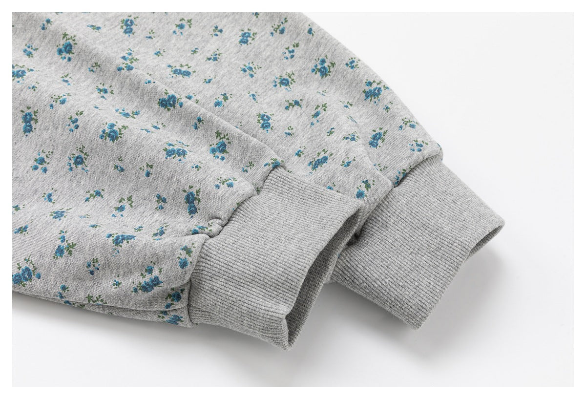 Close-up of the gray ribbed sleeve cuffs and blue floral print on a hoodie.