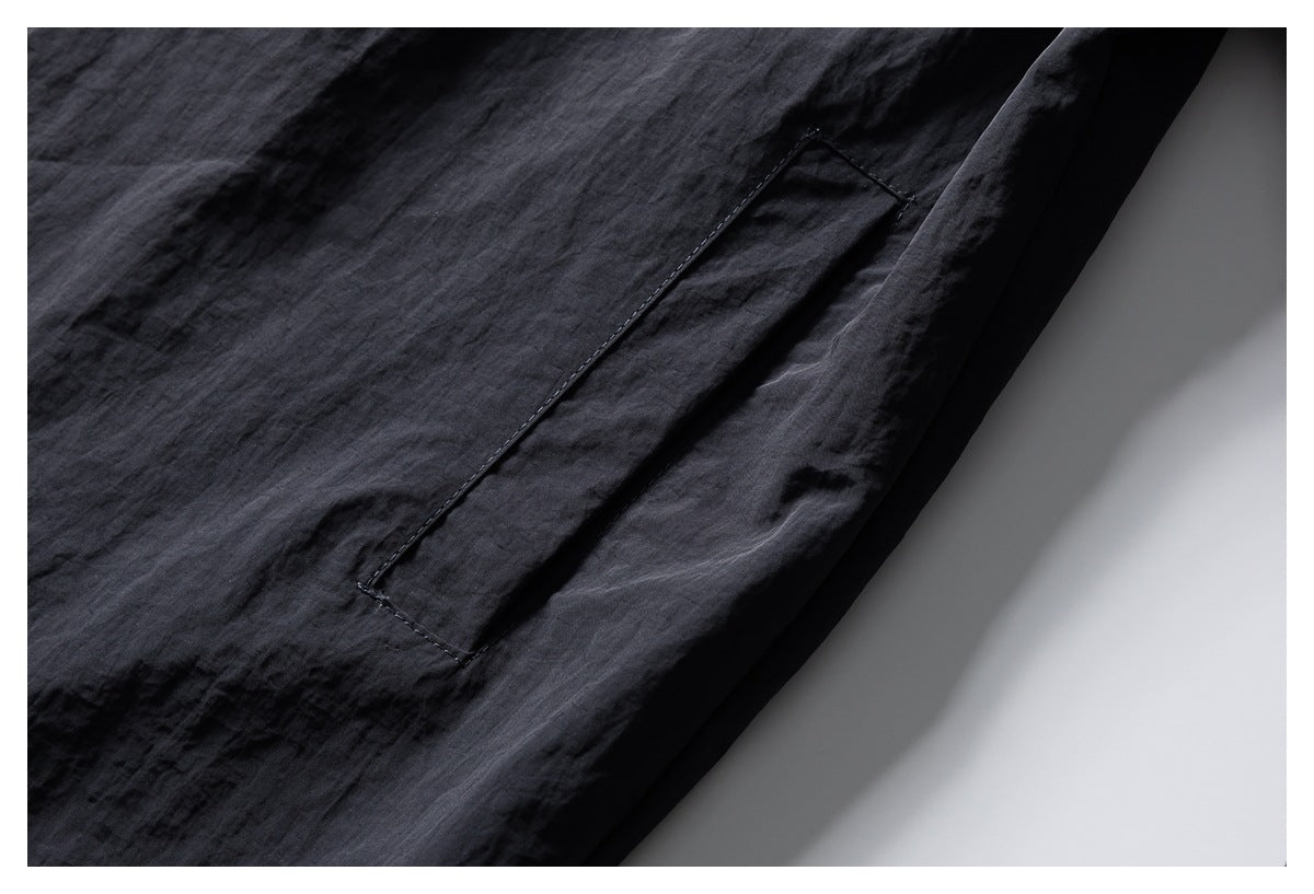 Close-up of a dark charcoal garment showing a stitched rectangular pocket.