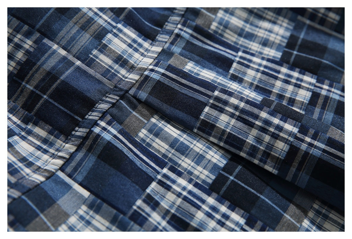 Close-up of navy and blue plaid shirt fabric with a stitched seam and folded edge.