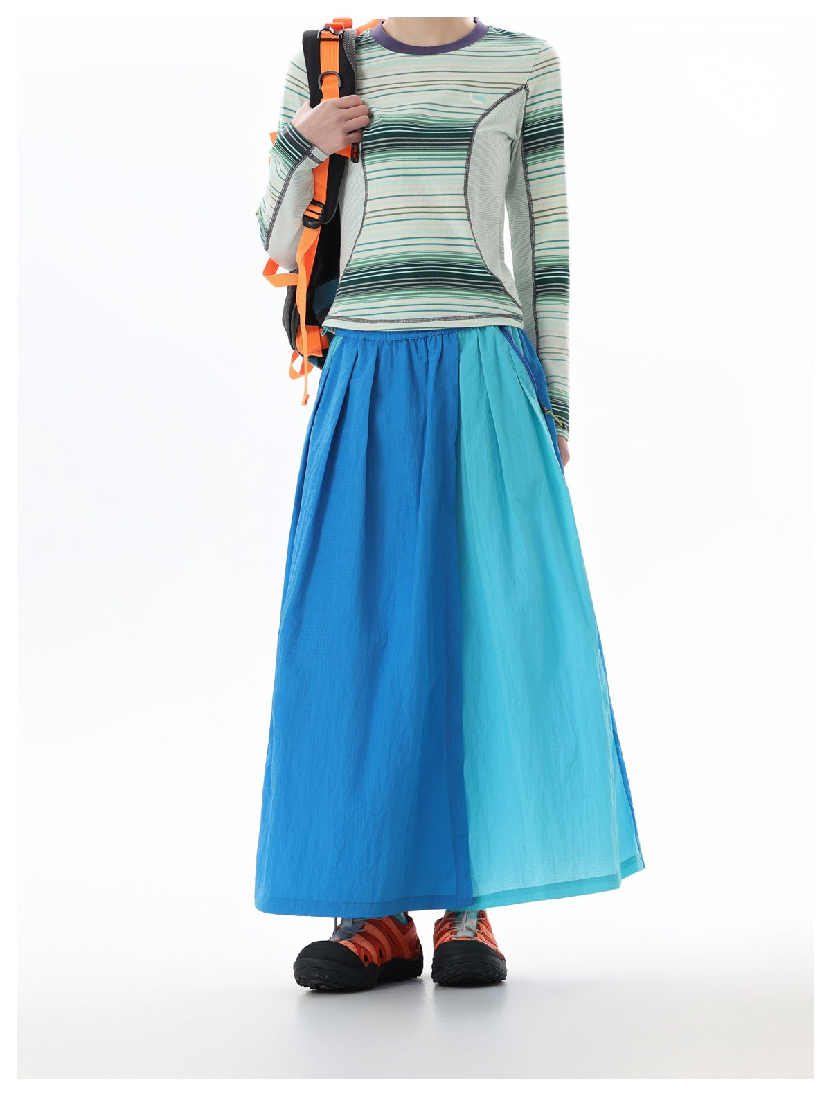 Front view of a model wearing a blue and aqua color-block maxi skirt with a fitted striped long-sleeve top.