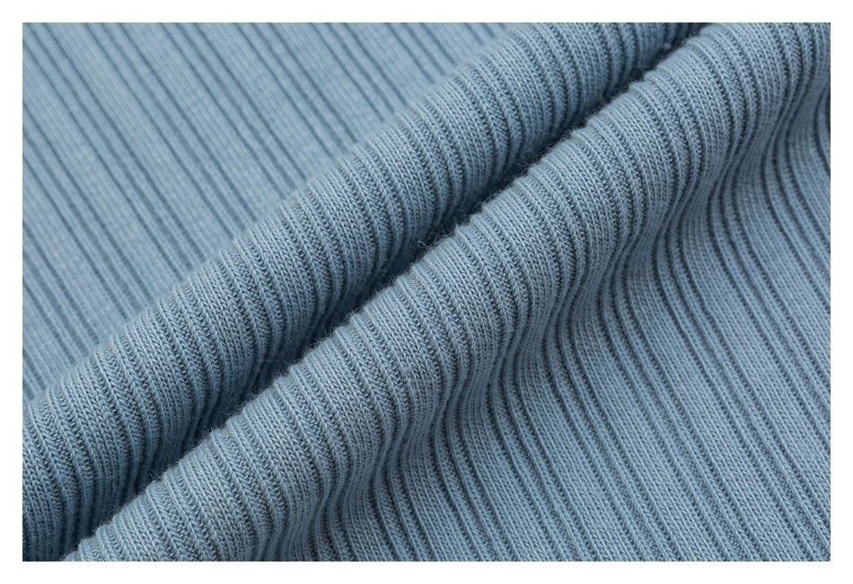 Macro view of the light blue top's fine vertical ribbed knit, draped into soft folds.