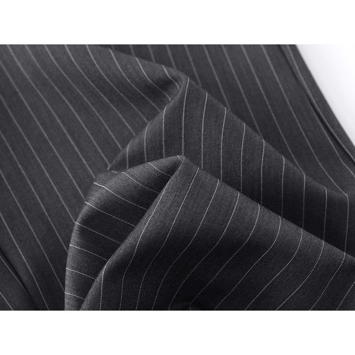 Close-up of charcoal fabric with thin light pinstripes and overlapping trouser folds.