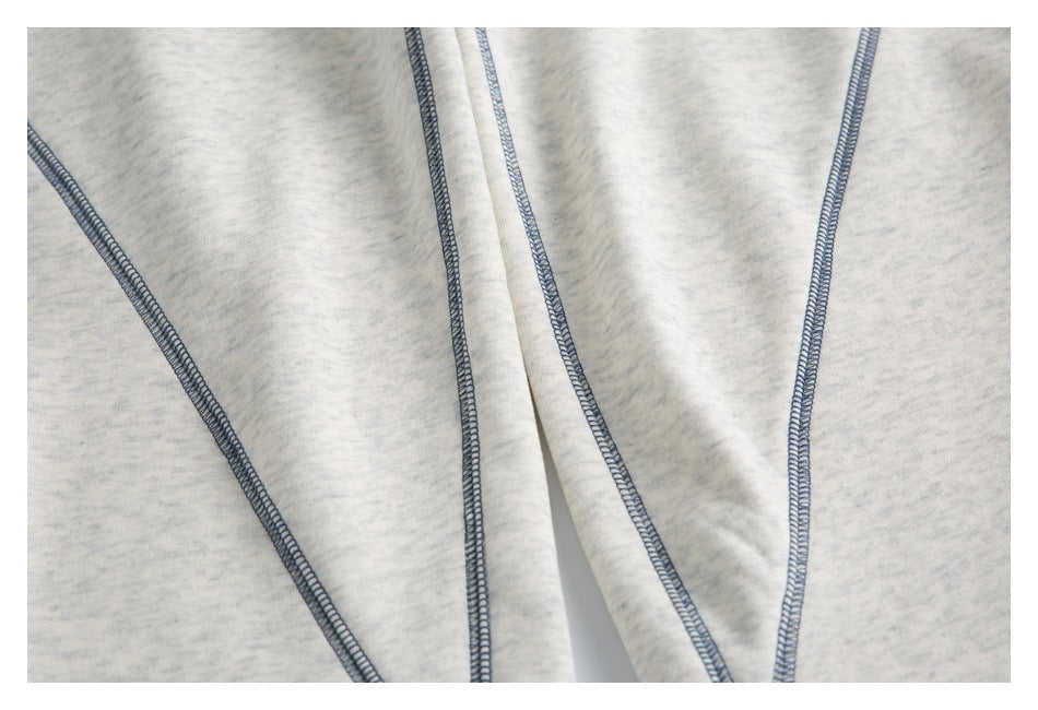 Close-up of blue-gray overlock stitching along the panels of light gray marled joggers.