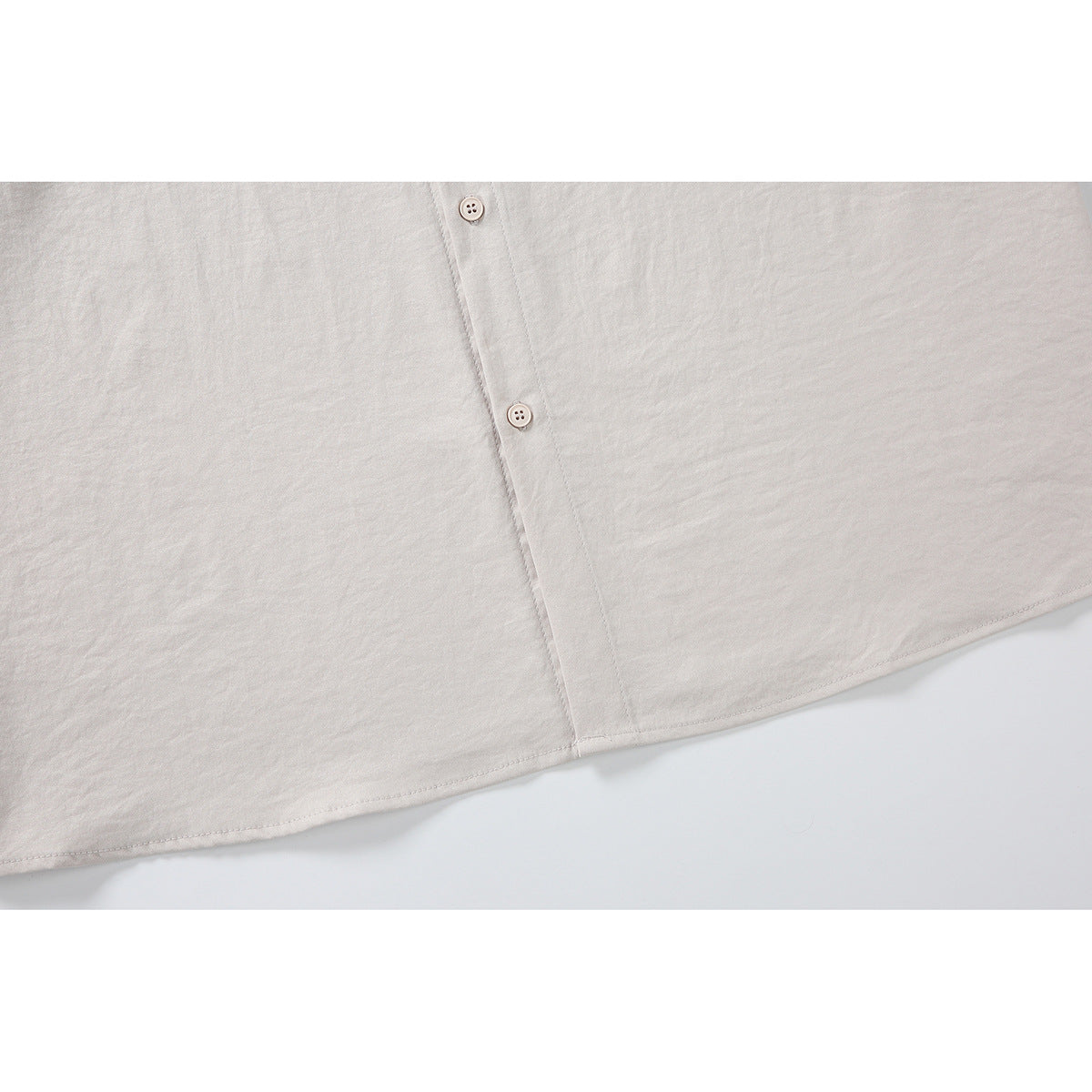 Close-up of the off-white shirt's button placket and curved hem.