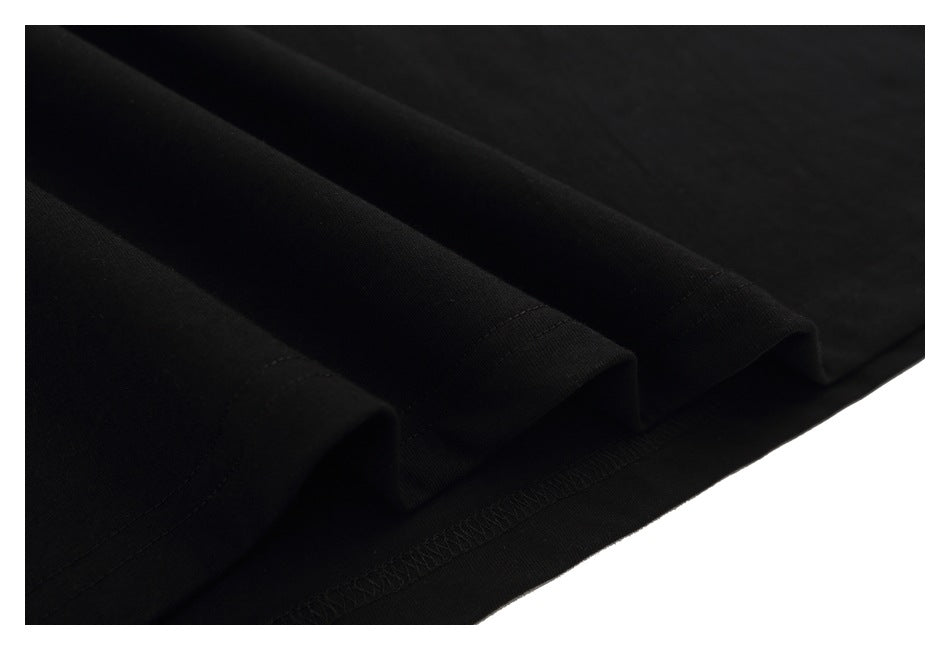 Close-up of black T-shirt fabric folded to show the stitched hem and overlock finish.