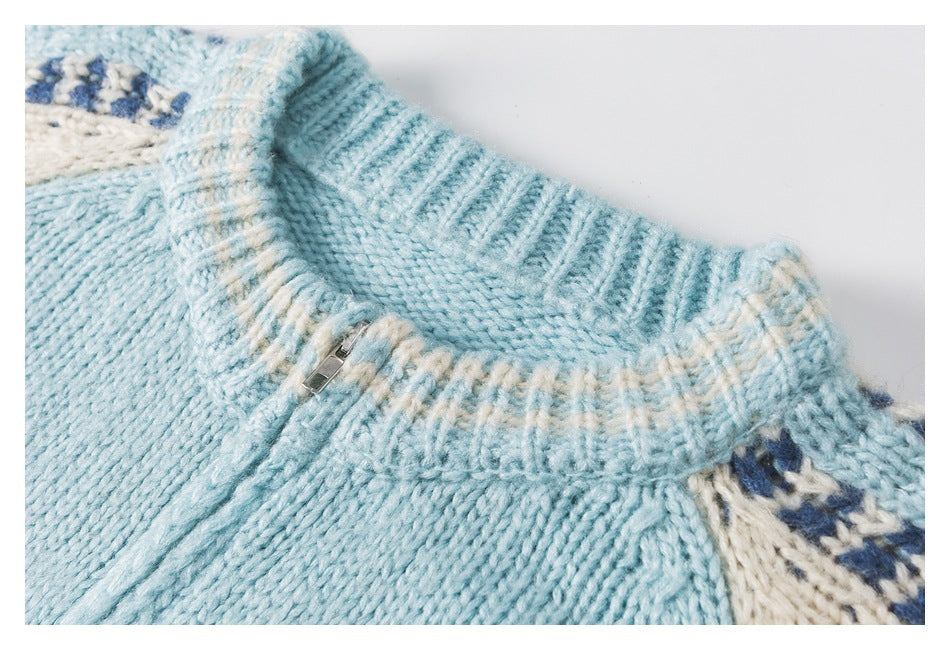 Close-up of an aqua knit garment's ribbed collar, short zipper, and cream-and-blue patterned trim.