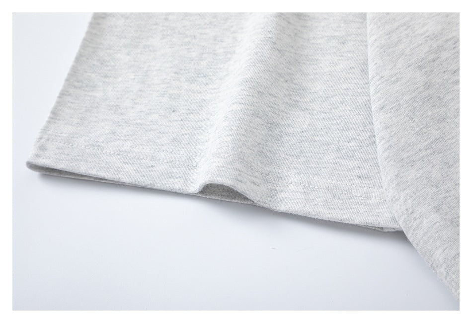 Close-up of a stitched hem on light gray heather T-shirt fabric.
