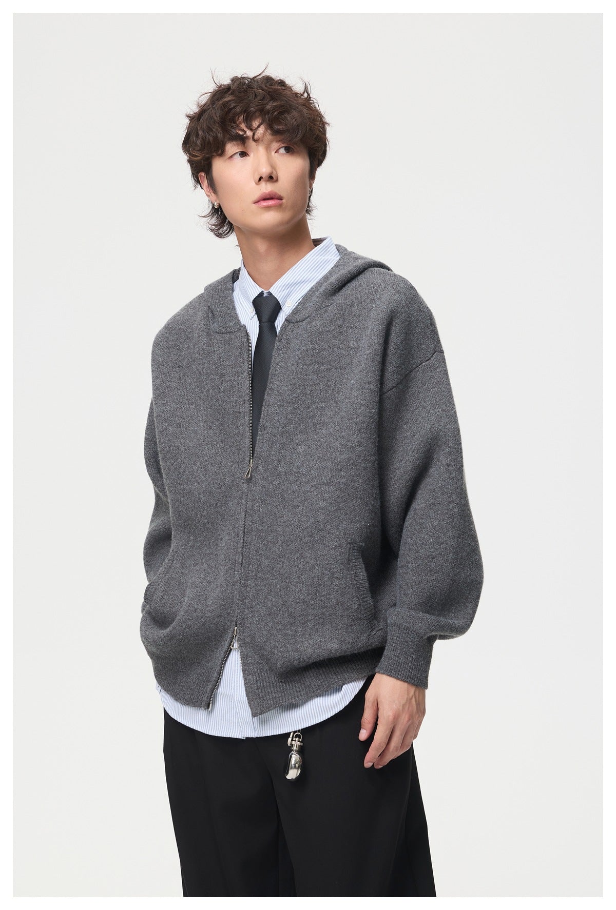 Model wearing a charcoal gray zip-front hooded cardigan over a striped shirt and tie.