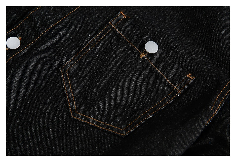 Close-up of a black denim pocket with orange topstitching and silver snap buttons.