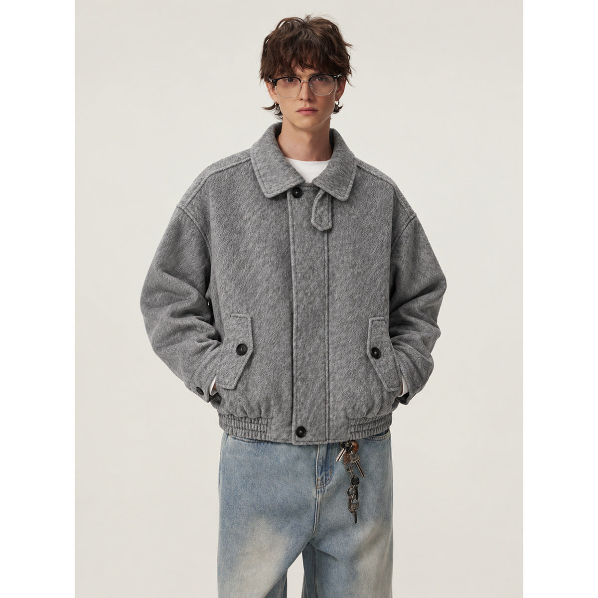 Front view of a model wearing a gray textured jacket with a wide collar, dark buttons, and flap pockets.