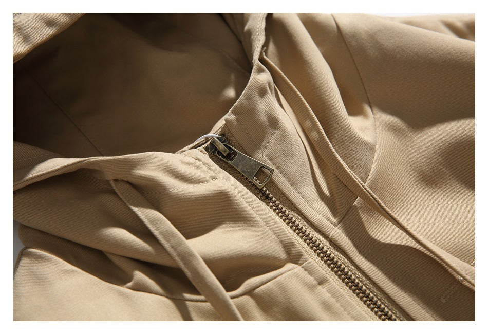 Close-up of the tan jacket's metal zipper, hood drawstrings, and front fabric.