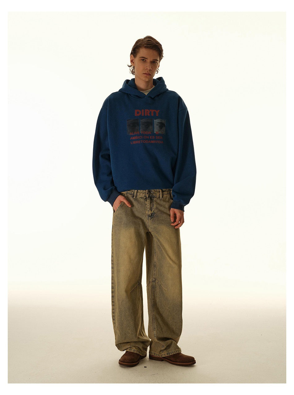 Full-length model wearing a navy graphic hoodie, loose tan jeans, and brown shoes against a light studio backdrop.