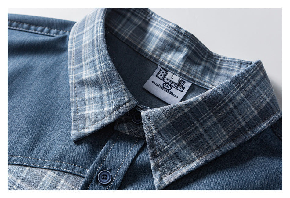 Close-up of a blue denim shirt collar with gray-blue plaid trim, dark buttons, and a sewn neck label.