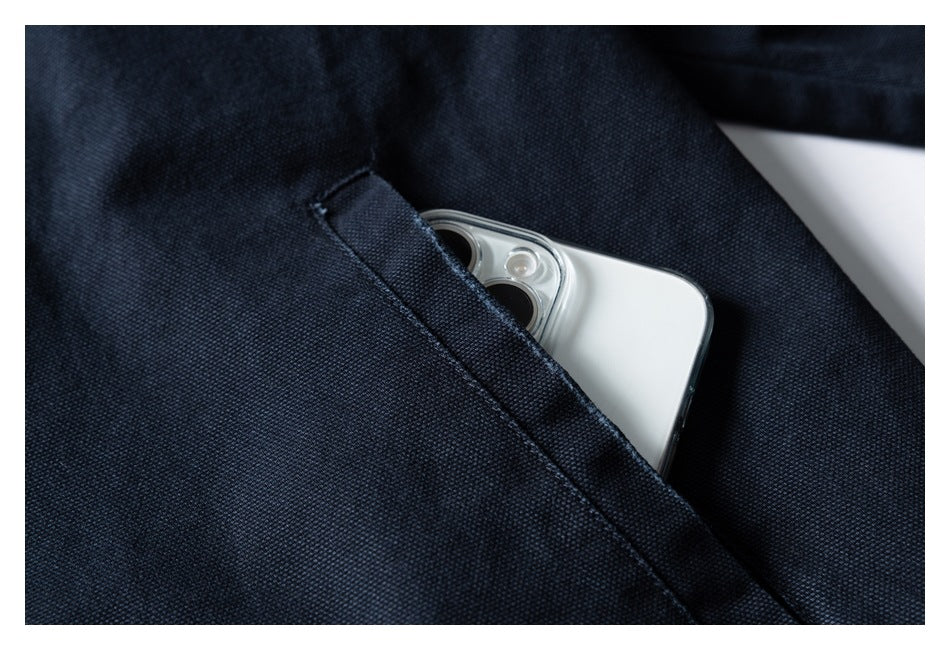 Close-up of a dark navy garment pocket with a white smartphone tucked inside.