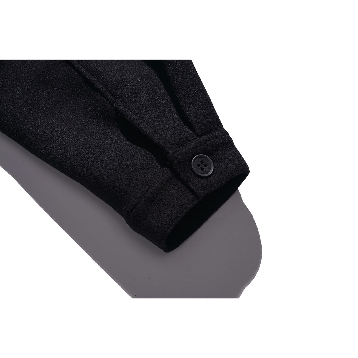 Close-up of a black jacket sleeve cuff with a dark button and stitched seam.