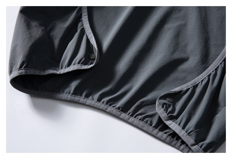 Close-up of dark gray jacket fabric with curved piped edges, gathered stitching, and two buttons.