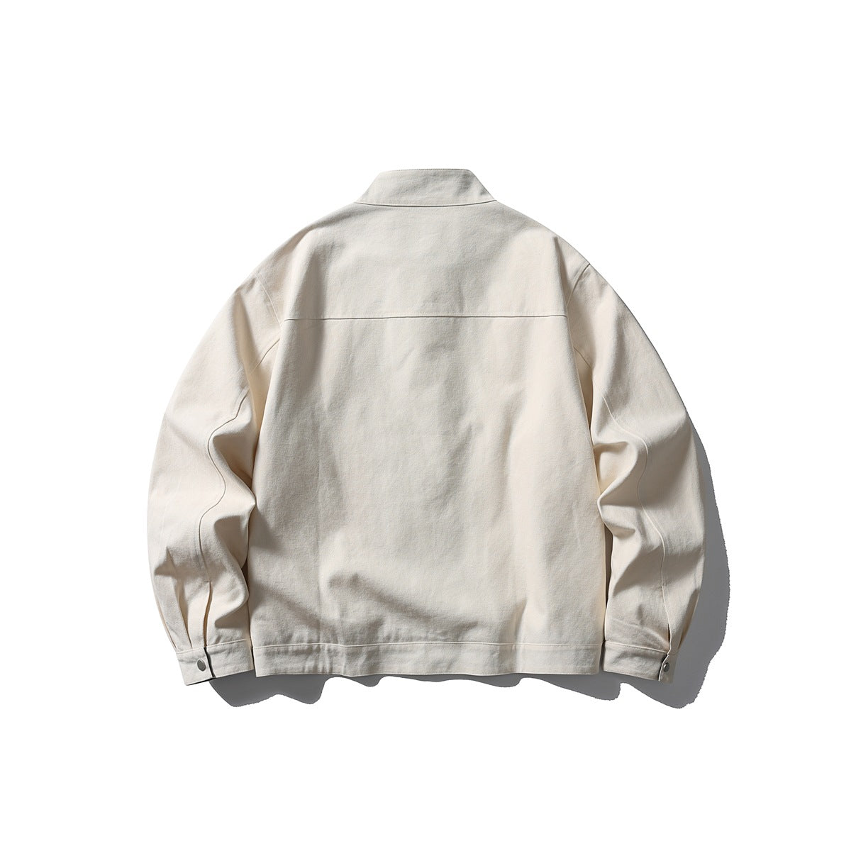 Back view of an ivory jacket laid flat, with a stand collar, long sleeves, snap cuffs and a plain back.
